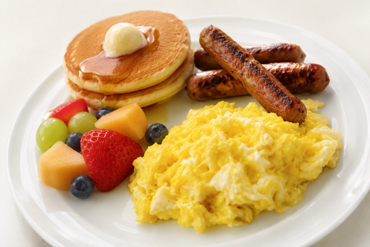 Plate of pancakes, scrambled eggs and sausage from a hot breakfast buffet